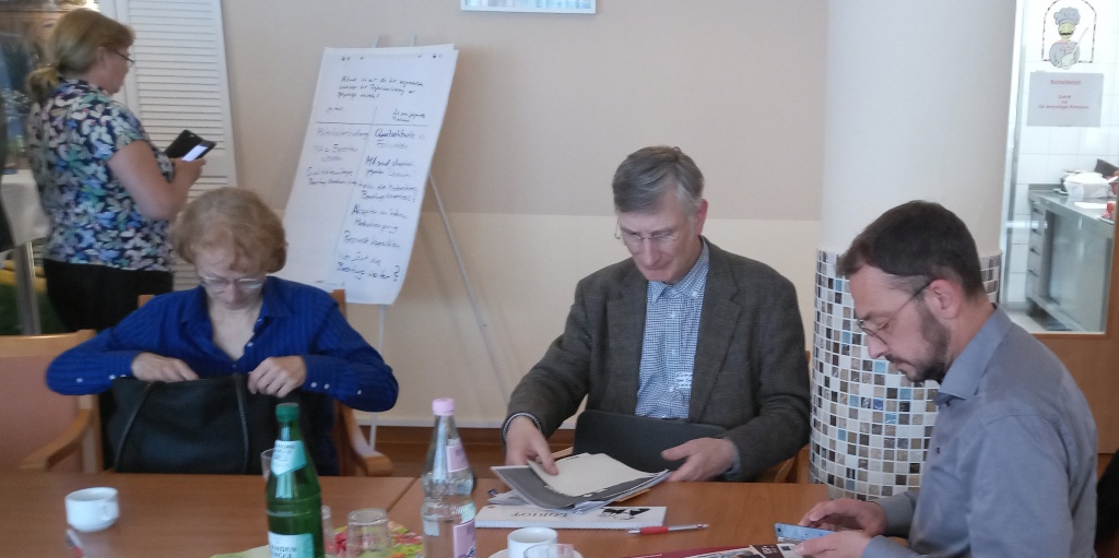 Foto: Teilnehmer_innen am Konferenztisch sitzend