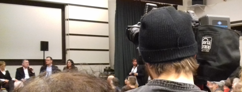 Foto: Kameramann im Publikum einer Podiumsdiskussion