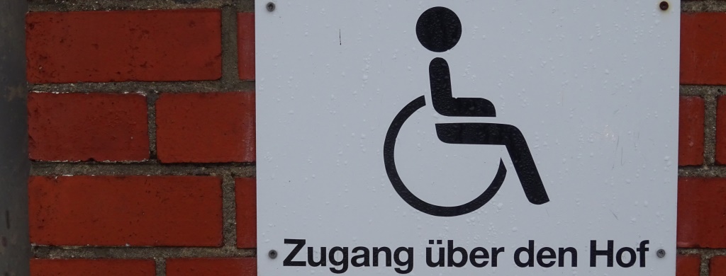 "Zugang über den Hof", Hinweis für Rollstuhl-Fahrer an Hausfassade